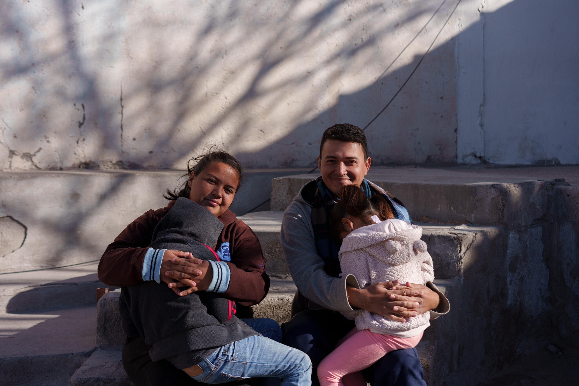 Natalia and José hold their two children. 