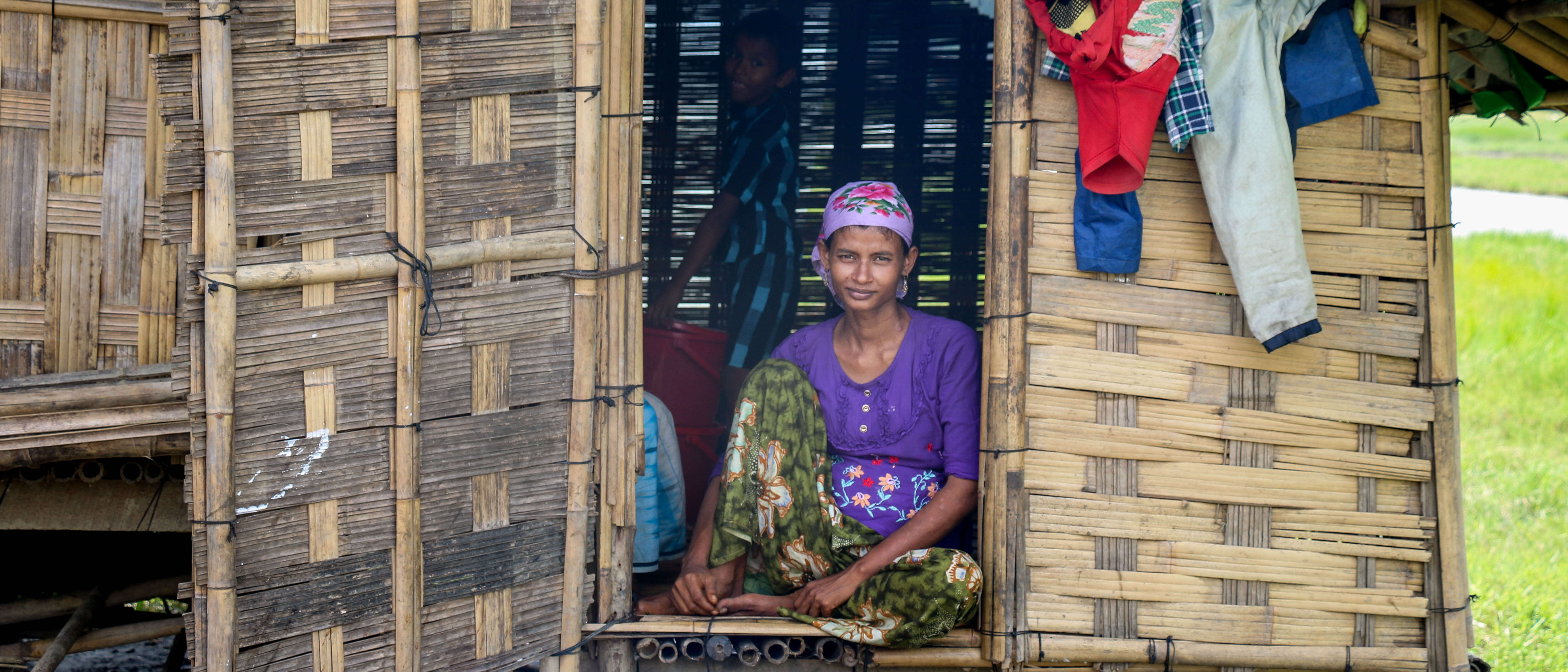 A woman poses for a photo while sitting in the opening of a doorframe.