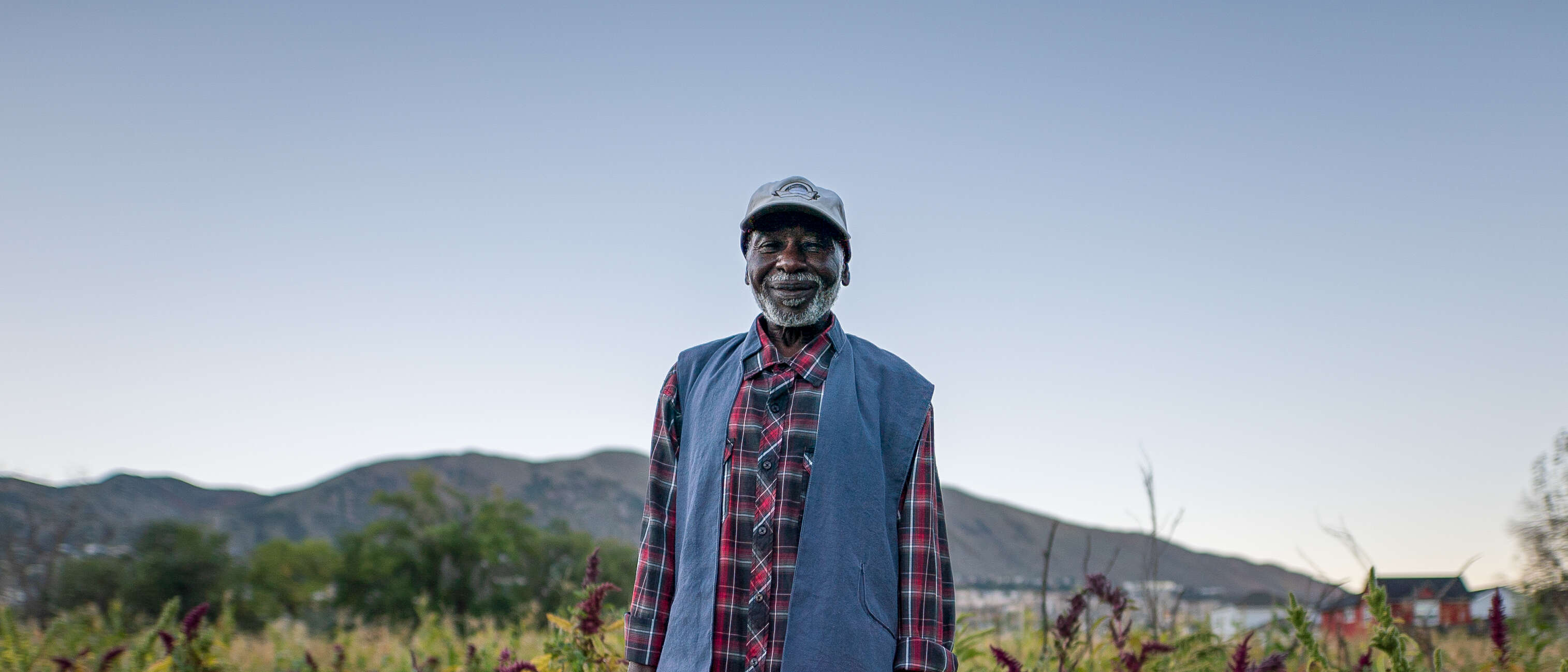 A man stands in a field and smiles while posing for a photo.